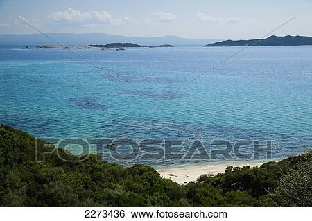 Stock Photograph - Greece, Halkidiki, Small secluded beach on the Mediterranean sea with the island of Ammouliani visible in the distance; Ouranoupoli. Fotosearch