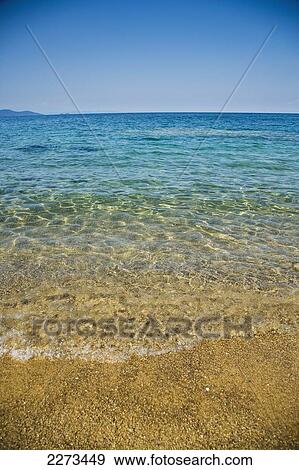 Greece, Halkidiki, Small waves lapping at shore on a sunny beach with crystal clear blue sea; Ierissos View Large Photo Image Stock Photo - Greece, Halkidiki, Small waves lapping at shore on a sunny beach with crystal clear blue sea; Ierissos. Fotosearch