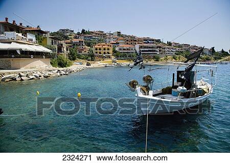 Stock Image - Greece, Halkidiki, Traditional wooden fishing boat moored in small harbour; Pirgadikia. Fotosearch