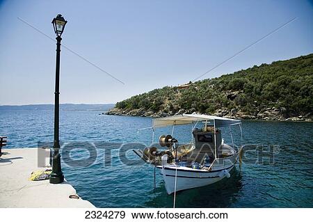 Stock Photo - Greece, Halkidiki, Traditional wooden fishing boat moored in small harbour; Pirgadikia. Fotosearch