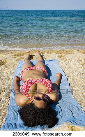 Stock Photo - Greece, Halkidiki, Woman sunbathing on beach; Ierissos. Fotosearch
