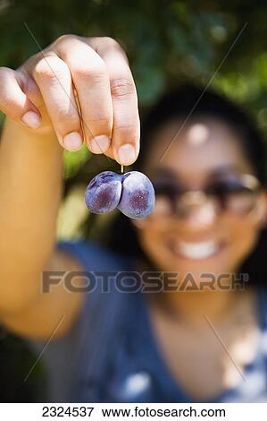 Stock Photo - Greece, Halkidiki, Young woman showing plums; Lerissos. Fotosearch