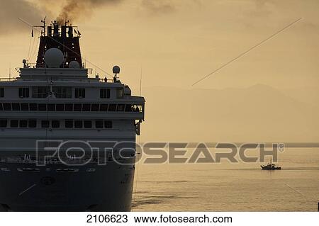 Stock Image - Greece, Small fishing boat beside large cruise ship at dawn; Corfu. Fotosearch