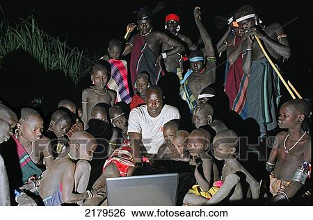 Group of Mursi tribal people looking in owe at the first Mursi owned laptop computer being operated in the deep of night. Makki / South Omo / Southern Nations, Nationalities & People's Region (Ethiopia). View Large Photo Image Stock Photograph - Group of Mursi tribal people looking in owe at the first Mursi owned laptop computer being operated in the deep of night. Makki / South Omo / Southern Nations, Nationalities & People's Region (Ethiopia).. Fotosearch
