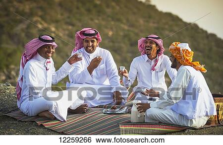 Stock Photograph - Group of Saudis drinking tea on top of mountain range; Taif, Saudi Arabia. Fotosearch