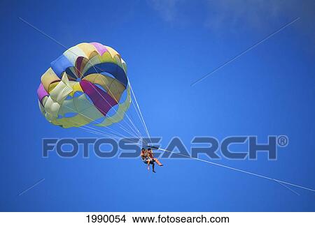 Picture - Guam, Cocos Island Resort, Couple In Blue Skies, Parasailing. Fotosearch