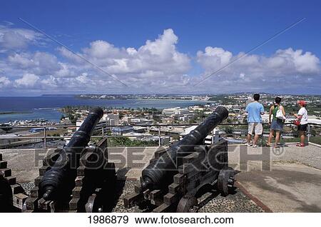 Stock Photo - Guam, Hagatna (Agana), Cannons At Fort Santa Agueda, Tourists Observing City Viewpoint.. Fotosearch