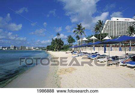 Stock Photo - Guam, Tumon Bay, Beautiful Beach, People Sunbathing On Beach Chairs.. Fotosearch