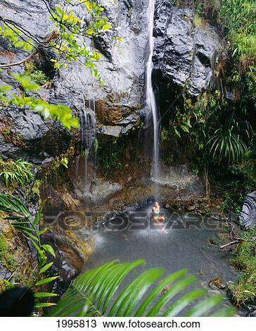 Stock Image - Guam, Yona, Upper Sigua Falls, Woman In Pool Under Waterfall. Fotosearch