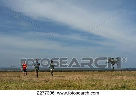 Stock Photograph - Guide and tourists on run along track with Mt Kenya behind, Ol Pejeta Conservancy; Kenya. Fotosearch