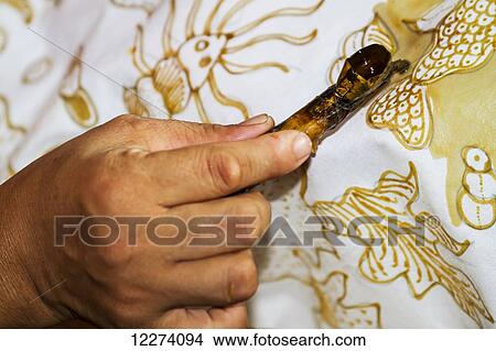 Hand of a craftswoman drawing intricate patterns by using a pen-like instrument, called canting, to apply hot wax to a fabric in the production of batik at Sarwidi's Batik workshop, Banyuripan-Bayat, Central Java, Indonesia View Large Photo Image Picture - Hand of a craftswoman drawing intricate patterns by using a pen-like instrument, called canting, to apply hot wax to a fabric in the production of batik at Sarwidi's Batik workshop, Banyuripan-Bayat, Central Java, Indonesia. Fotosearch