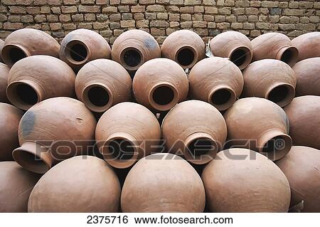 Stock Photograph - Handmade traditional ceramic water pots lying upurchased beside a kiln; India. Fotosearch