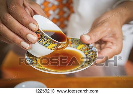 Hands holding traditional Ethiopian coffee cup pouring coffee into saucer; Takoma Park, Maryland, United States of America View Large Photo Image Stock Image - Hands holding traditional Ethiopian coffee cup pouring coffee into saucer; Takoma Park, Maryland, United States of America. Fotosearch