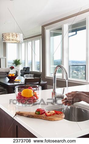 Stock Photo - Hands Washing Red Peppers In Kitchen With Water View; Langford, Vancouver Island, British Columbia, Canada. Fotosearch