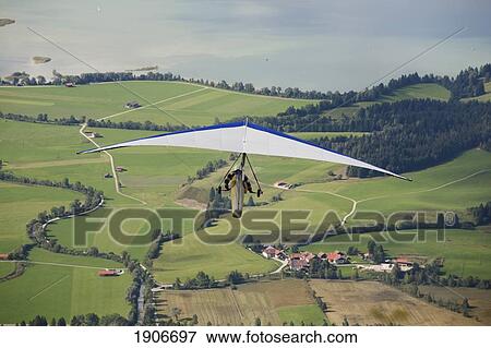 Stock Photo - Hang Glider Flying Over Fields And Lake Below; Schwangau, Germany. Fotosearch