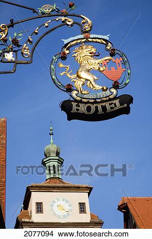Picture - Hanging Sign For A Hotel And A Clock Tower On A Building; Rothenburg Ob Der Tauber Bavaria Germany. Fotosearch
