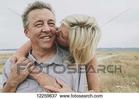 Stock Photo - Happy senior couple embracing on a grassy beach; Coquitlam, British Columbia, Canada. Fotosearch
