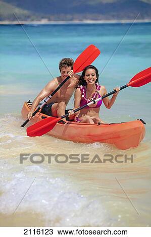 Stock Image - Hawaii, A young couple paddling their kayak.. Fotosearch