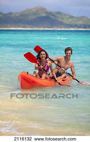 Stock Image - Hawaii, A young couple paddling their kayak.. Fotosearch