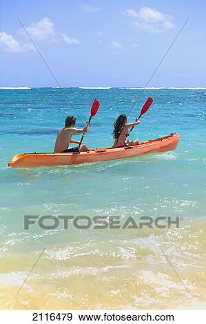 Stock Photo - Hawaii, A young couple paddling their kayak.. Fotosearch