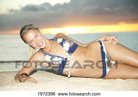 Stock Photograph - Hawaii, An Attractive Young Woman Lays In Sand On Beach.. Fotosearch