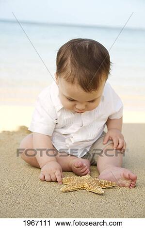 Stock Image - Hawaii, Baby Boy On Beach With Starfish.. Fotosearch