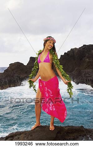 Stock Photograph - Hawaii, Beautiful Hawaiian Girl Wearing Bright Pink Pareo, Green Lei And Haku, Standing On Rocky Shoreline. Fotosearch