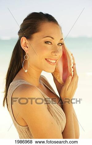 Hawaii, Beautiful Sophisticated Girl Listens To A Seashell. View Large Photo Image Stock Photo - Hawaii, Beautiful Sophisticated Girl Listens To A Seashell.. Fotosearch