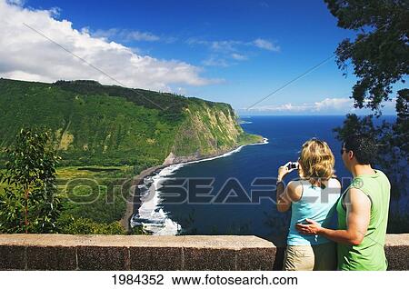 Stock Image - Hawaii, Big Island, Hamakua Coast, Waipio Valley, Couple Taking A Photo From The Lookout.. Fotosearch