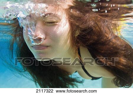 Stock Image - Hawaii, Big Island, Hapuna Bay, Young brunette woman swimming underwater.. Fotosearch
