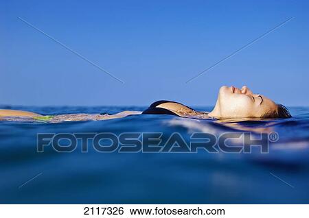 Stock Photograph - Hawaii, Big Island, Hapuna Bay, Young brunette woman floating above water.. Fotosearch