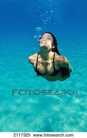 Stock Photography - Hawaii, Big Island, Hapuna Bay, Young brunette woman swimming underwater.. Fotosearch