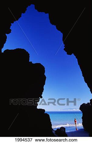 Stock Photo - Hawaii, Big Island, Hapuna Beach Park, View From Inside Sea Cave, Woman Walks Along Shoreline.. Fotosearch