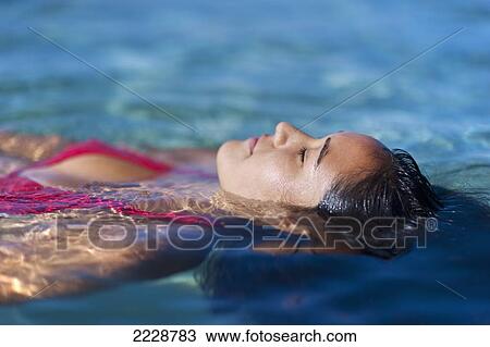 Stock Image - Hawaii, Big Island, Honaunau Bay, Beautiful Youn Woman Floating At Oceans Surface.. Fotosearch