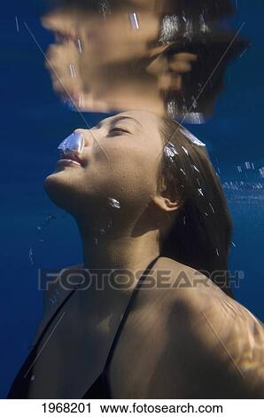 Stock Image - Hawaii, Big Island, Honaunau Bay, Young Woman Exhales As She Swims To The Surface.. Fotosearch