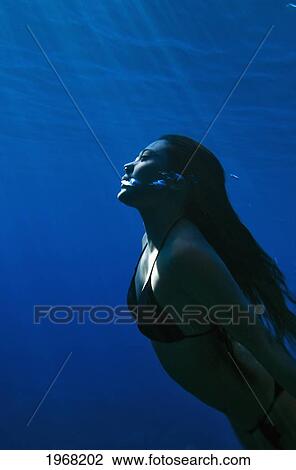 Stock Image - Hawaii, Big Island, Honaunau Bay, Young Woman Exhales As She Swims To The Surface.. Fotosearch