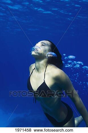 Stock Photo - Hawaii, Big Island, Honaunau Bay, Young Woman Exhales As She Swims To Ocean Surface.. Fotosearch