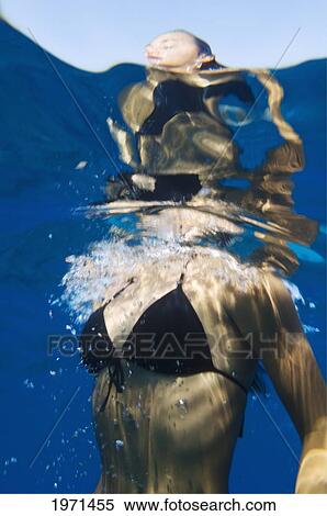 Stock Photography - Hawaii, Big Island, Honaunau Bay, Young Woman Breaking Ocean Surface While Swimming.. Fotosearch