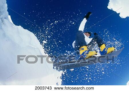 Stock Image - Hawaii, Big Island, Mauna Kea, Close-Up Action Shot Of Snowboarder In Air, View From Beneath Clear Blue Sky. Fotosearch
