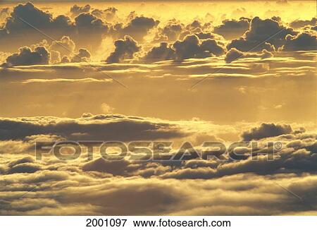 Stock Photo - Hawaii, Big Island, Mauna Kea, Yellow Sunset Sky View From Above And Through Puffy Clouds. Fotosearch