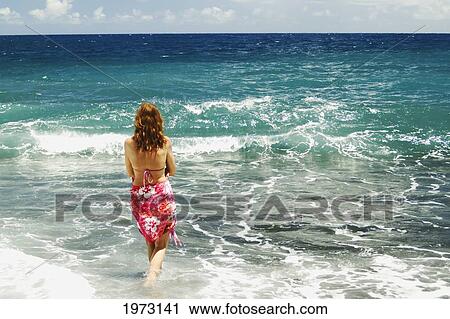 Stock Image - Hawaii, Big Island, Pololu Valley Black Sand Beach, Woman Standing In The Shorebreak.. Fotosearch