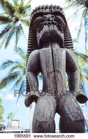 Stock Image - Hawaii, Big Island, Puuhonua O Honaunau, City Of Refuge, Ki'i Against Blue Sky And Palm Trees.. Fotosearch