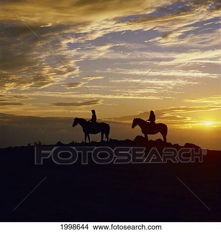 Picture - Hawaii, Big Island, Waialae Iki, Couple Horseback Riding At Sunset, Silhouette. Fotosearch
