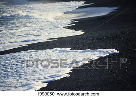 Stock Image - Hawaii, Black Sand Beach, White Foamy Water Along Shoreline. Fotosearch