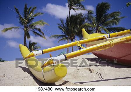 Stock Image - Hawaii, Close-Up Of Yellow Outrigger Canoe On Beach, Palm Trees And Blue Sky In Background.. Fotosearch