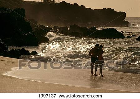 Stock Photo - Hawaii, Couple Walking On The Beach, Reflection Of Sun On The Waves, A05E. Fotosearch