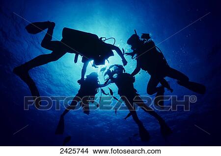 Picture - Hawaii, Divers silhouetted by sunburst. Fotosearch