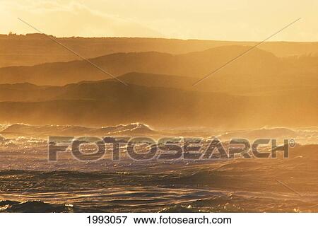 Stock Photo - Hawaii, Golden Storm Waves, Hilly Land In Back Ground.. Fotosearch