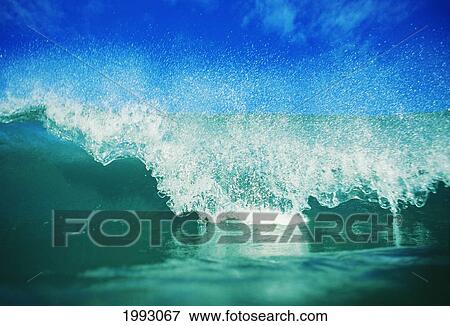Stock Photo - Hawaii, Green Wave Breaking Front View With Blue Skies In Background.. Fotosearch