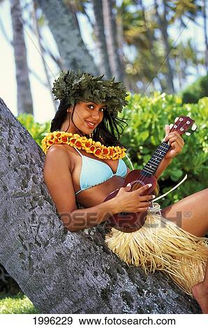 Stock Photo - Hawaii, Hula Girl With Haku And Ukulele Leaning Against Tree. Fotosearch